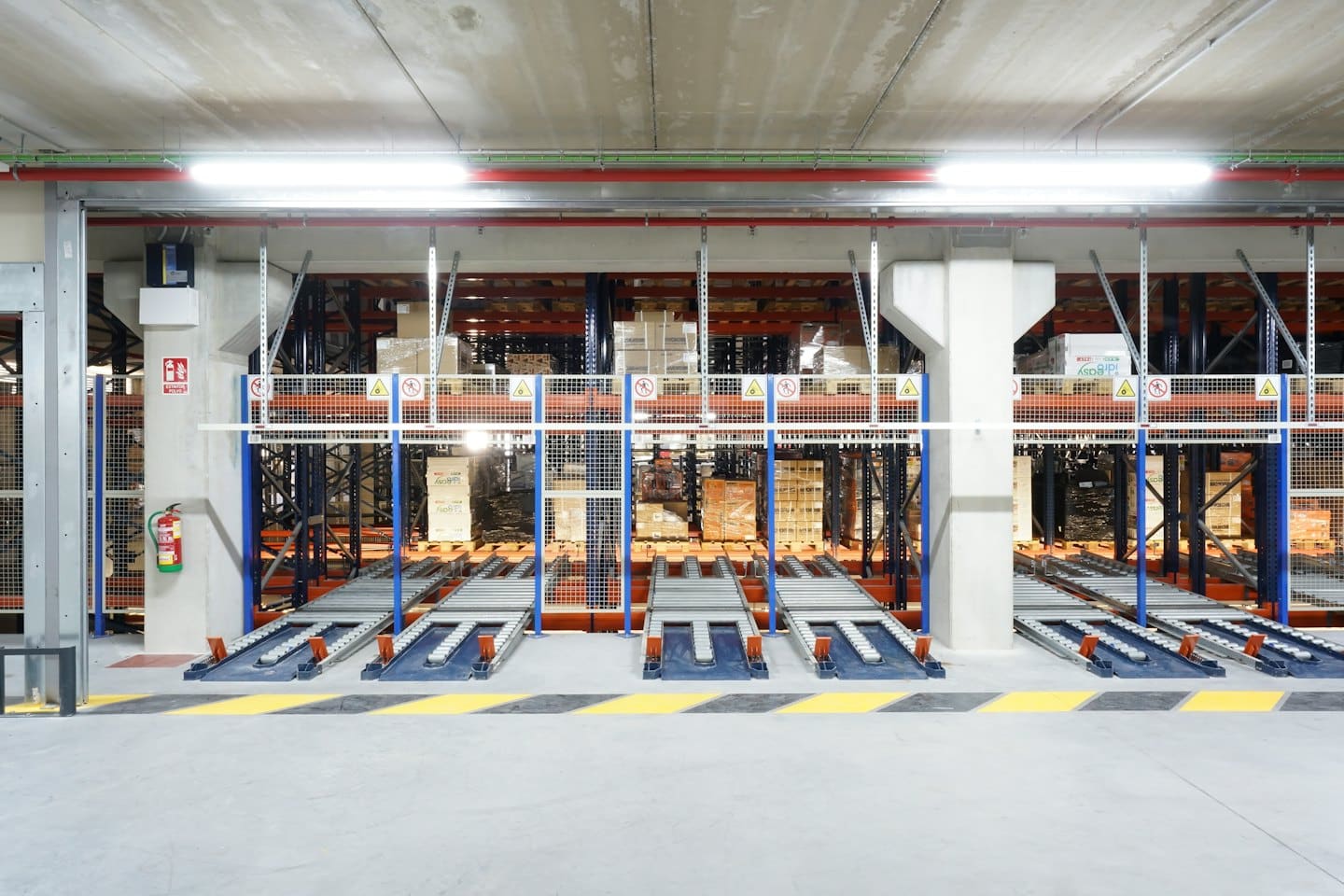 Automated warehouse with pallet racking and conveyor systems.